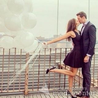 Девушка держит шарики и целует мужчину. На крыше. Фото для цитаты.